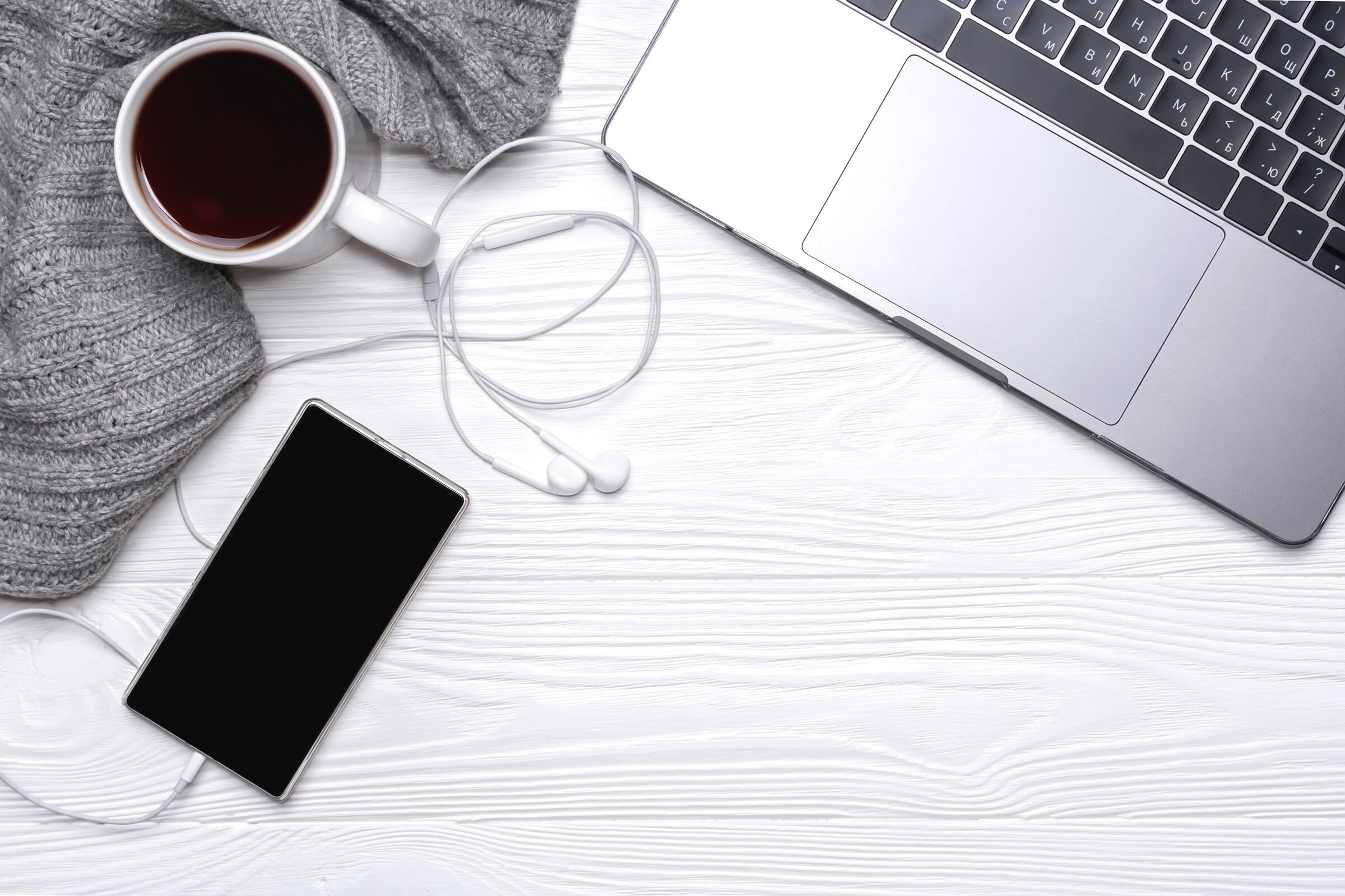 Flat lay office workplace. Laptop, cup, headphones, telephone,scarf on a white